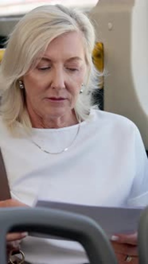 Woman Reads Document on Bus