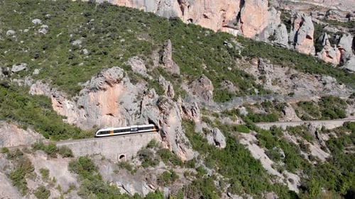Aerial, drone following a train among a rugged terrain in Catalonia