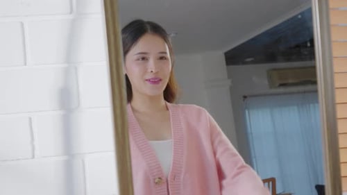 Schöne asiatische junge Frau blickt in den Spiegel und strahlt Stolz und Selbstvertrauen aus, ein Spiegelbild von sich selbst