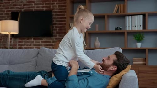 Father and daughter playing together on couch