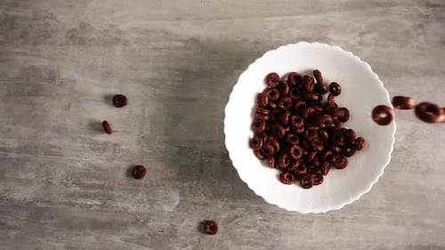 Chocolate Cereal Loops Falling into White Bowl