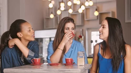 Three Women Talking and Laughing at Indoor Cafe