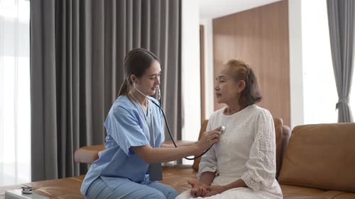 Nurse is take care senior woman at home. Using stethoscope.