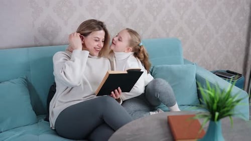 Woman and Child Reading Book on Blue Couch