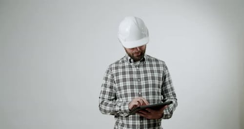 Engineer in Hard Hat Uses Tablet on White Background