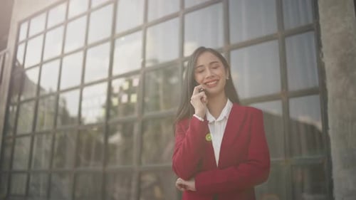Businesswoman talking to clients and colleague on the phone and working on laptop outside the office