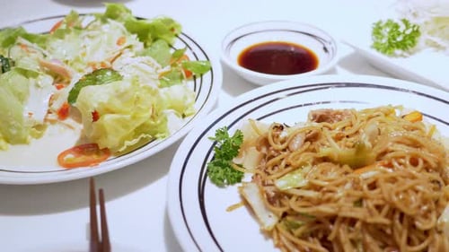 Panning from the left to the right on a meal served in a restaurant, a plate of salad, stir-fried no