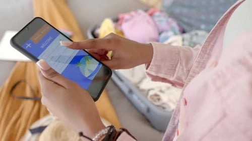 A young African American woman is browsing a travel booking app on a smartphone