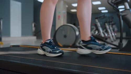 Person Walking on Treadmill in Blurred Gym Room
