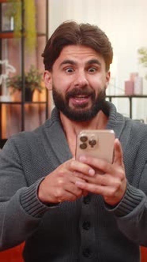 Excited man receives good news on smartphone indoors