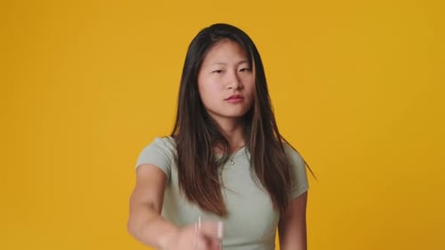 Young woman making denial gesture looking at camera, isolated over yellow background in studio