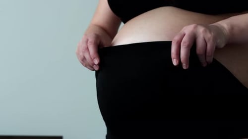 Pregnant Woman Puts On High Waisted Bottoms