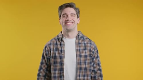 Young Man Smiling in Front of Yellow Backdrop
