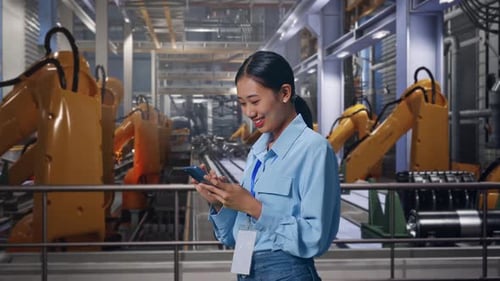 Smiling Woman Using Smartphone in Automated Factory
