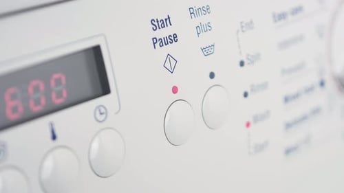 Close up shot of slow motion finger pressing start pause button on washing machine dial rinse clothi