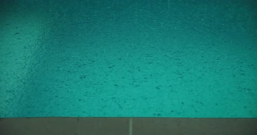 El agua de lluvia salpica una piscina turquesa durante un aguacero tropical en Bali