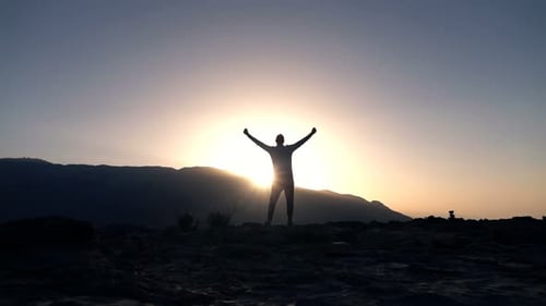 Man Silhouette Standing on Hill with Arms Raised