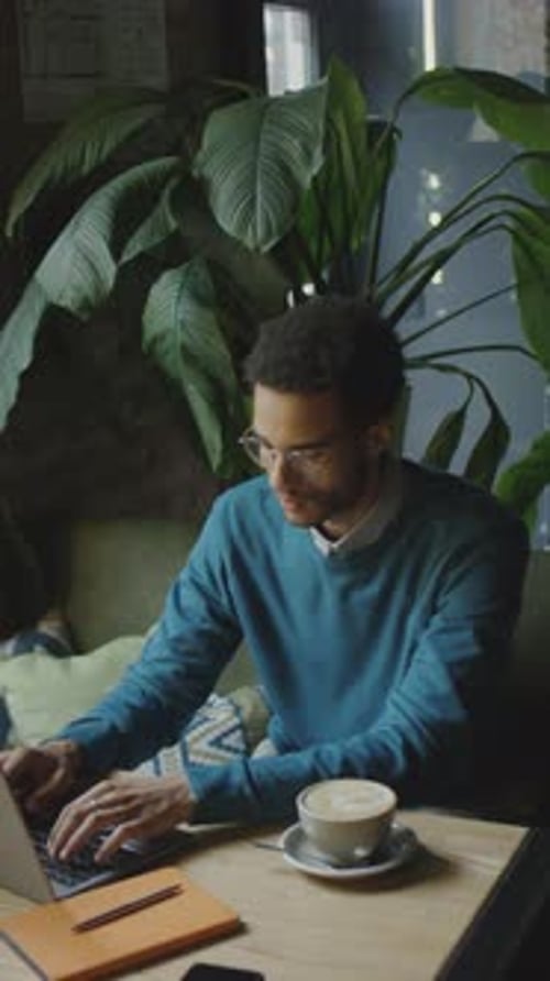 Männlicher Freelancer benutzt Laptop im Coffeeshop