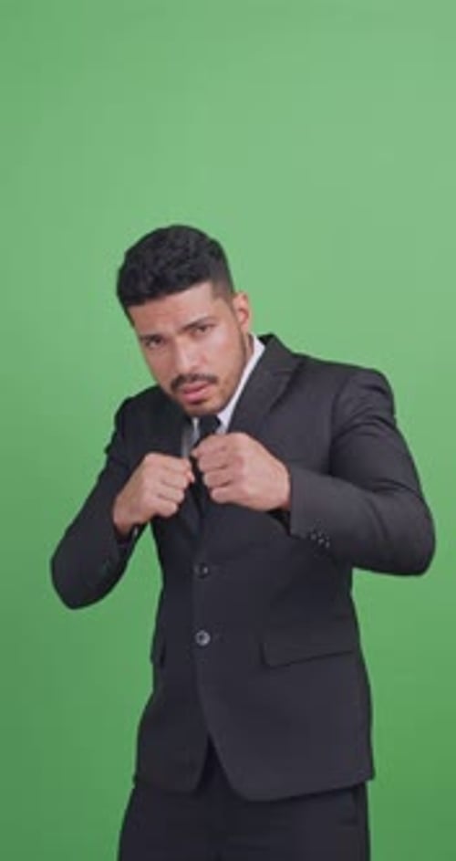 Asian businessman in a black suit is fighting for something. Isolated on green background in studio.