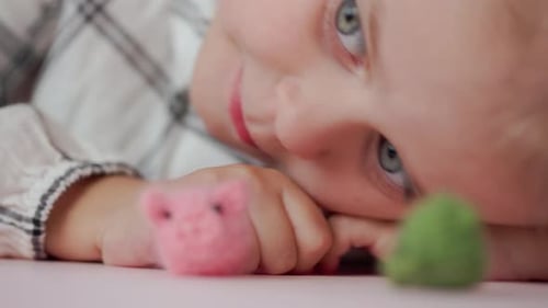 Mädchen spielt mit kleinen gestrickten Tierspielzeugen in einem Zimmer zu Hause
