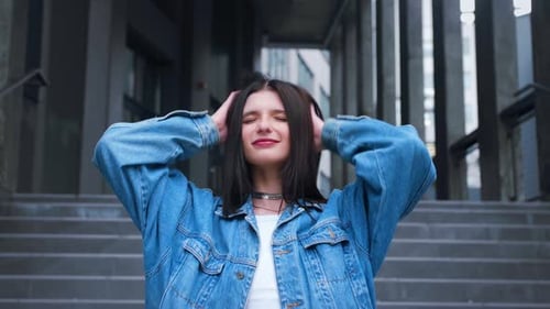 Beautiful Fashionable Model Smiles Posing Outdoors and Straightens Her Long Hair Outdoor Urban City