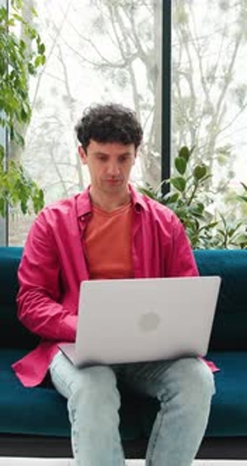 Young Man Opens Laptop on Couch