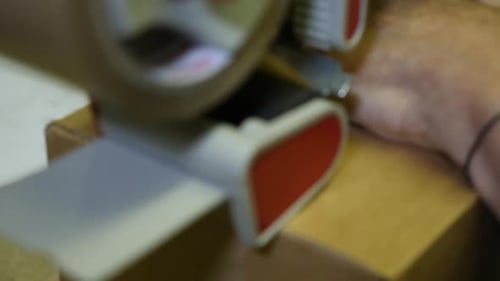 Hands closing pack with tape. Close-up