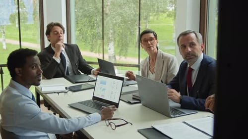 Business Meeting with Charts and Graphs on Laptops