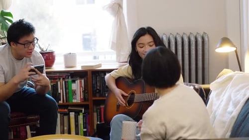 Friends Relaxing Indoors, Woman Plays Guitar