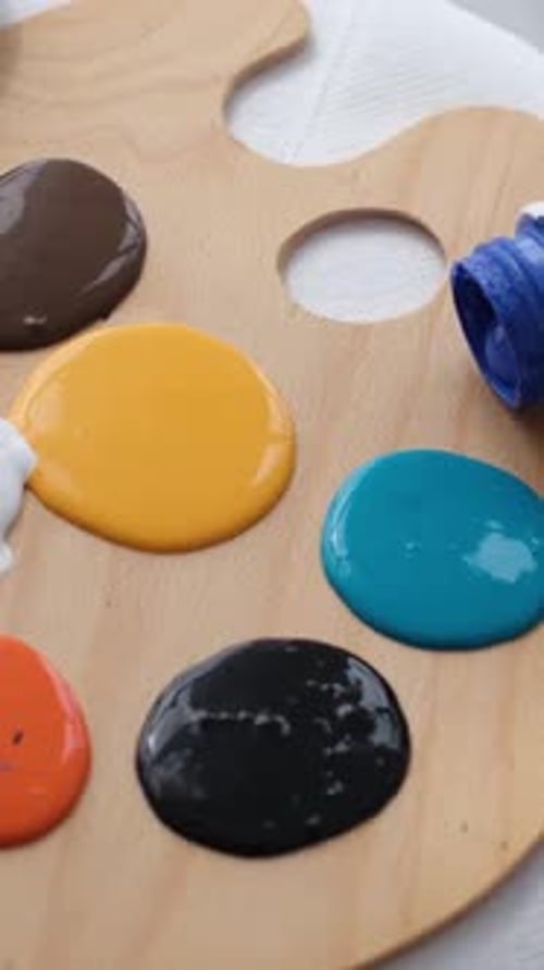 Mittlere Nahaufnahme eines modernen Künstlers, der blaue Acrylfarbe auf eine Palette gießt (Vertikales Video)