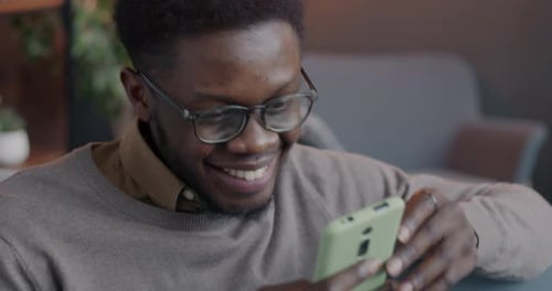 Man Smiling While Using Smartphone Indoors