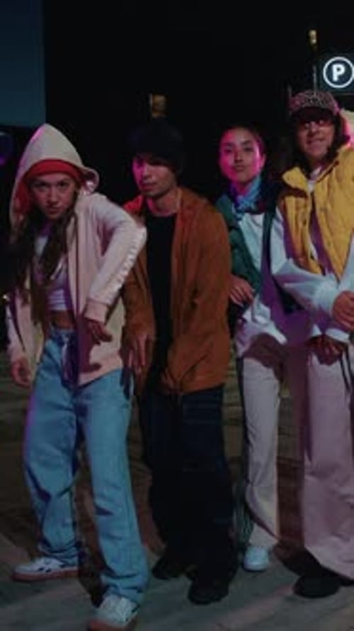 Young Urban Dancers Perform at Night with Vibrant Neon Lights in the Background