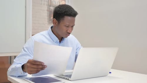 Young Adult Working with Laptop and Paper