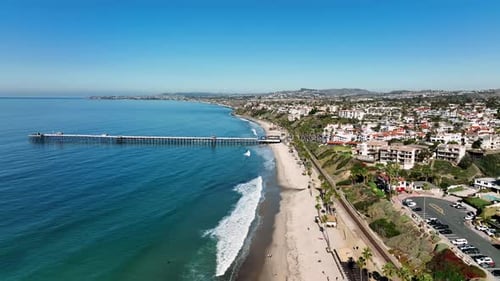 Drone flying forward near San Clemente. Cinematic video of a San Clemente Pier. Surfers ride waves i