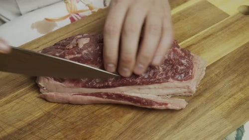 Cutting off extra fat from meat steak on the cutting board. Close up shot.