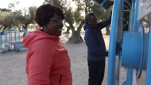 Smiling Senior Woman and Man Exercising at Outdoor Fitness Station