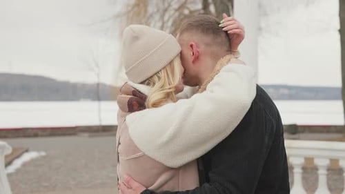 Happy couple in love having a great time in a winter park near a lake. Man and woman dancing
