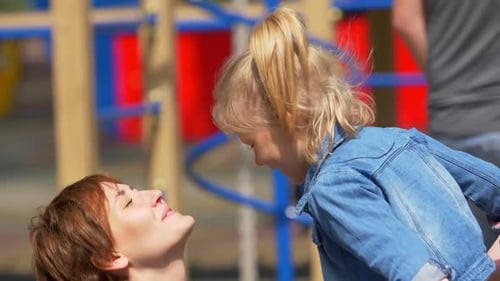Happy mother and child daughter hugging at playground: love and family concept