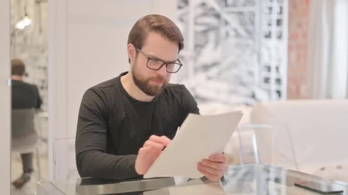 Man Reads Good News and Celebrates at Table