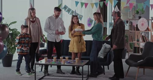 Family celebrates birthday with cake and presents indoors
