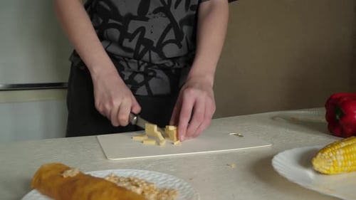 Person Dicing Cheese on Cutting Board for Meal