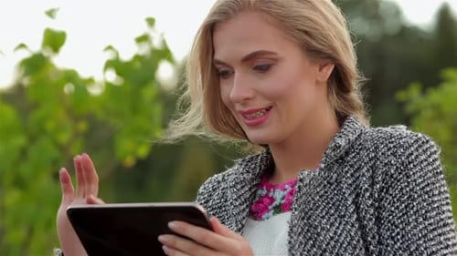 Woman Using Tablet Device Near Green Foliage