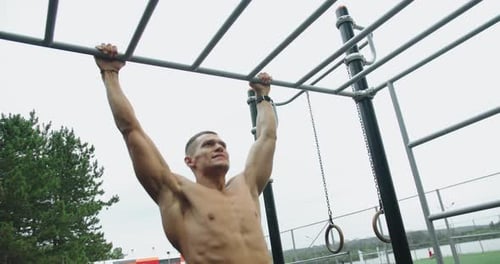 Young Athletic Man Exercising Outdoors and Pull Up on Horizontal Bar