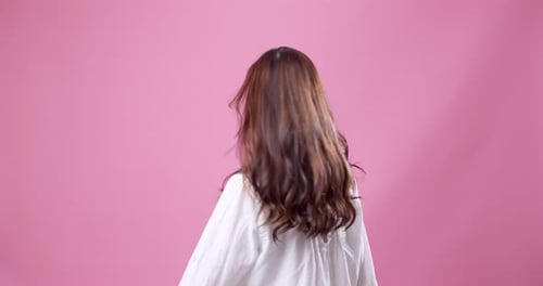 Young Asian woman in advertising studio twirling in front of camera showing her long hair and saying