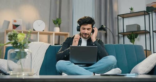 Young Adult Working on Laptop with Headphones at Home