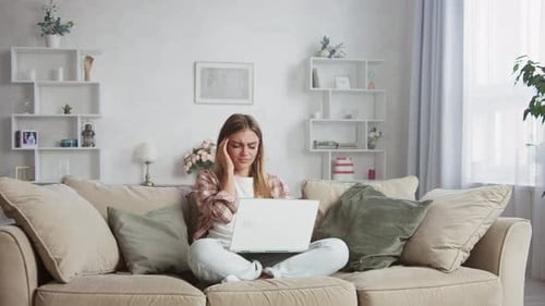 Junge Frau wird gestresst, wenn sie von zu Hause aus arbeitet, Wohnzimmer