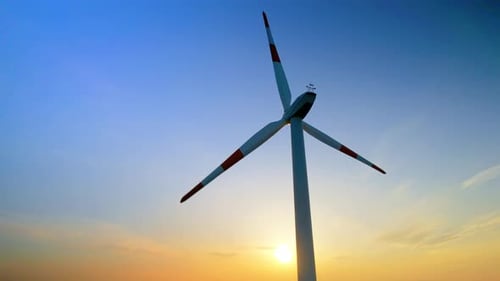 Aerial drone view of a working wind turbine. Setting over Sun on the background