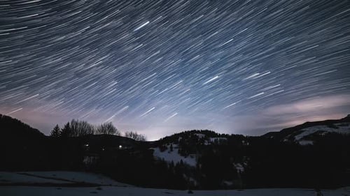 Rotating Star Trails Over Snowy Mountain Range
