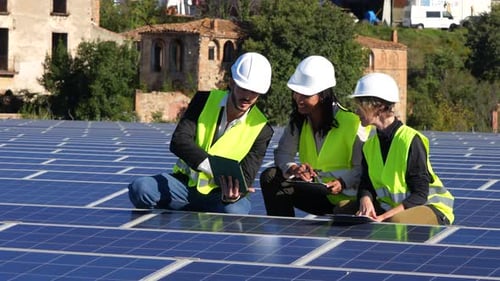 Vielfältiges Ingenieurteam inspiziert Sonnenkollektoren und verwendet Tablets