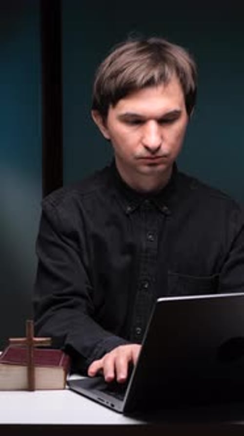 Vertical Video Priest Holding Cross and Leading Online Church Service with Laptop and Bible